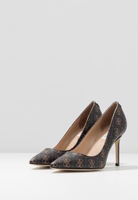 Escarpins à bout pointu en matériau texturé noir avec un motif de logo doré, talon stiletto fin et doublure beige.