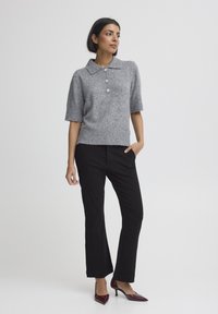 Svetlosivý krátky sveter s golierom, tromi gombíkmi a rebrovaným lemom; skombinovaný s čiernymi nohavicami s rovnými nohavicami a bordovými podpätkami.