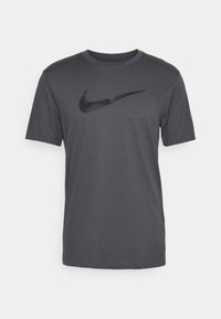 Szara koszulka z krótkim rękawem wykonana z miękkiego materiału, z dużym czarnym logo Nike na przodzie i okrągłym dekoltem.