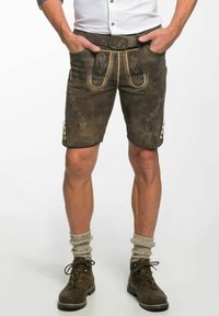 Bruna lädershorts med dekorativ broderi, framfickor och knappdetaljer. Bärs med mörka stövlar och grå stickade strumpor.