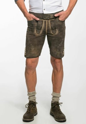 Braune Leder-Shorts mit dekorativer Naht, zwei Fronttaschen und Knöpfen an der Seite. Getragen mit kniehohen Socken und Stiefeln.