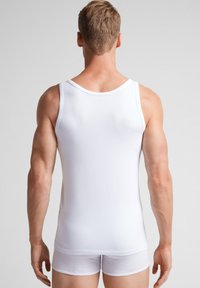 Witte katoenen tanktop met een ronde hals en slank ontwerp, voorzien van een soepele textuur en contrasterende witte elastische afwerking.