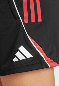 Black athletic shorts made of lightweight fabric featuring red stripes and accents, with white Adidas logo at the hem and contrasting piping.