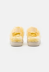 Yellow fluffy sandals with a textured exterior, featuring a cushioned sole and a branded strap in light orange with white lettering.