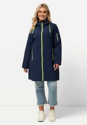 Veste imperméable marine avec capuche, fermeture éclair frontale et accents vert lime contrastants. Dotée de poches zippées sur les côtés et les bras. Coupe décontractée.
