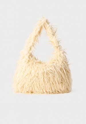 Sac à main duveteux de couleur crème avec une poignée triangulaire et une longue texture de fourrure hirsute sur un fond uni.