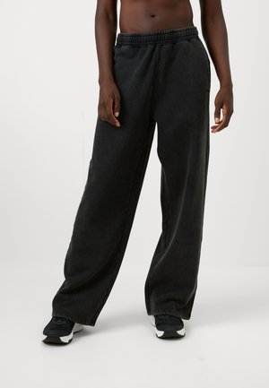 Pantaloni in felpa neri a gamba larga con un elastico in vita, realizzati in un tessuto morbido, con una texture liscia e dettagli di cucitura minimi.