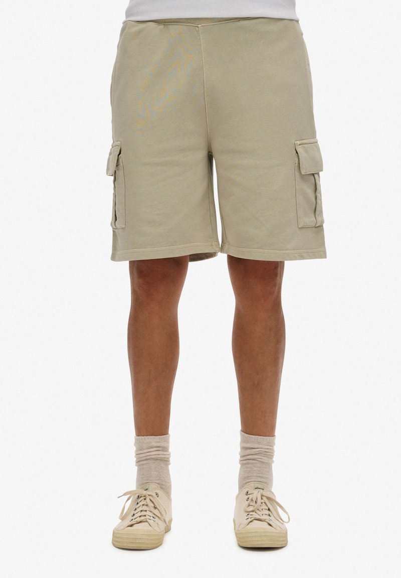 Beige cargoshorts met twee zijzakken, gestikte details en een losse pasvorm. Het materiaal lijkt zacht met een textuurafwerking.