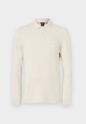 Langarm polo shirt in lichtbeige, gemaakt van gladde stof, met een polokraag, een knoopsluiting met twee knopen en een klein logopatch op de borst.