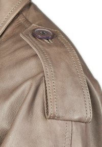 Braune Lederjacke im Detail, mit einer strukturierten Oberfläche, ausgeprägten Nähten und einem großen Knopfakzent auf dem Schulterriegel.
