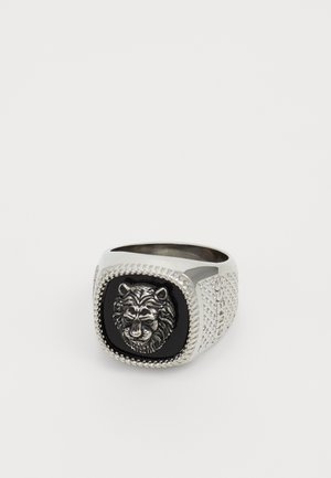 Sidabrinis metalinis žiedas, turintis liūto galvos dizainą juodo fono fone, su tekstūruotu detalizavimu ant juostos ir kvadratine forma.