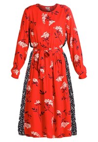 Robe midi rouge à manches longues avec motifs floraux blancs, panneaux latéraux floraux bleu marine, encolure ronde et ceinture à nouer à la taille.