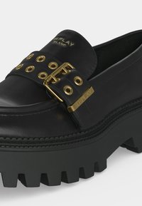 Mocassin en cuir noir à semelle épaisse avec boucle dorée et œillets, "REPLAY MILANO" embossé sur la bride et la languette.