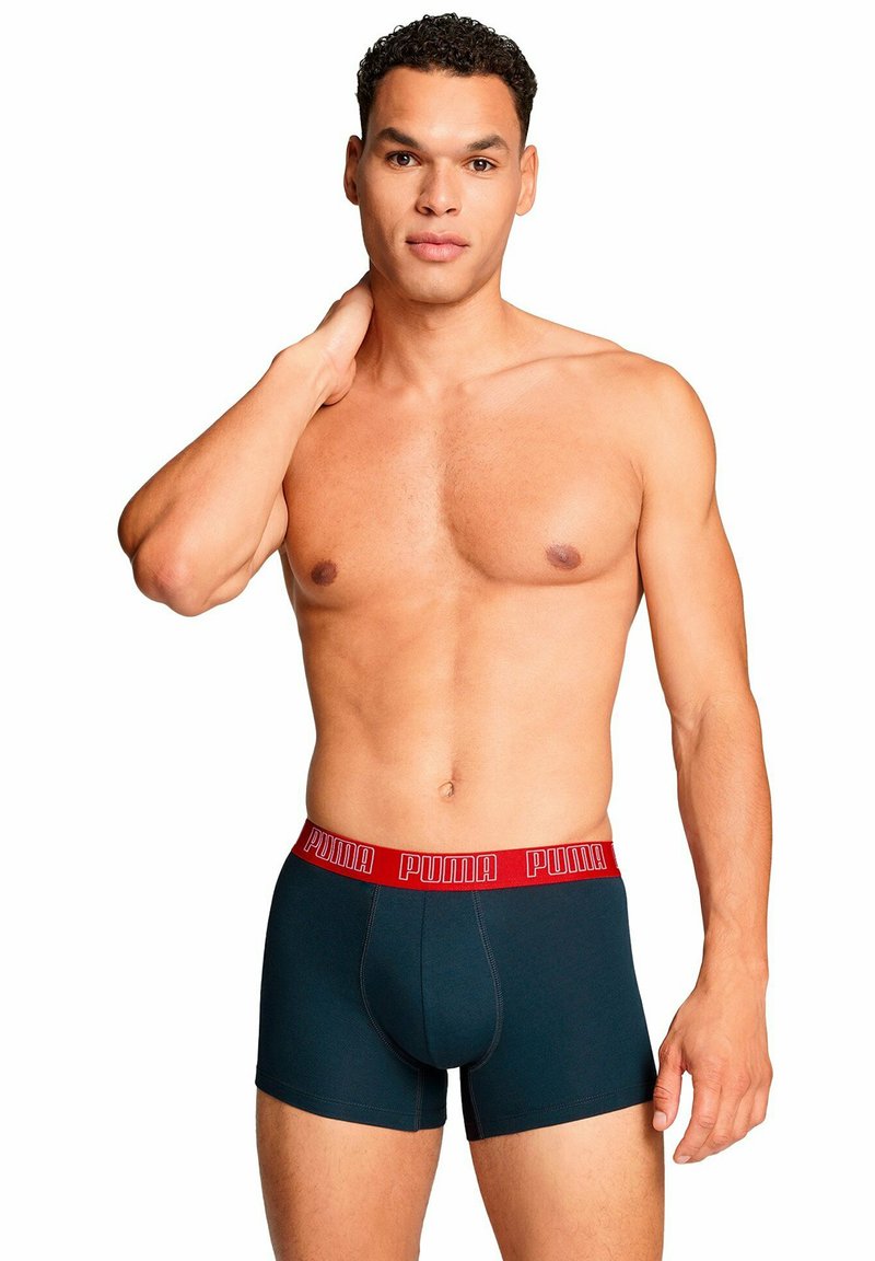 Boxer aderenti blu scuro con una banda elastica marchiata rossa. Il tessuto appare liscio e attillato, mettendo in risalto un design e una silhouette classici.