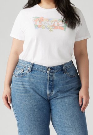 Valkoinen puuvillapaita, jossa on värikäs kukkakuvioinen Levi's-logo, yhdistettynä korkeavyötäröisiin sinisiin farkkuihin, joissa on klassinen istuvuus ja etutaskut.