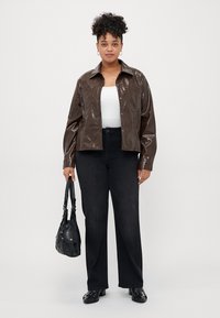 Brun, glänsande, konstläderjacka med knappframställning och spetsig krage. Kombinerad med svarta vida jeans och en svart handväska.