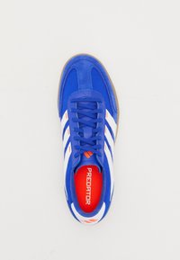 Zapatilla azul con rayas blancas, acentos naranjas, diseño de encaje ajustado y plantilla roja etiquetada "PREDATOR" sobre un fondo blanco.