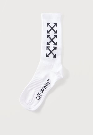Fehér bokazokni fekete, átlósan keresztbe tett nyíldíszítéssel a vádlin, valamint "Off-white" felirattal a láb boltozatán.