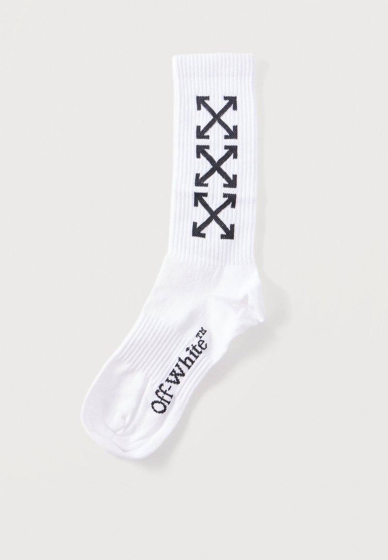 Chaussette blanche montante avec un motif de flèches croisées noires sur le mollet et le texte "Off-white" sur la voûte plantaire.