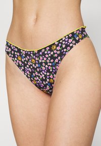 Calções de bikini pretos com um padrão floral em rosa, amarelo e roxo. Com uma cintura amarela.