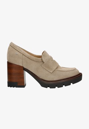 Beige suede block-heeled loafers with a rounded toe and front strap detail, featuring a patterned wooden heel and rugged black outsole.