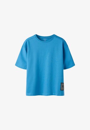 Plava pamučna majica kratkih rukava s okruglim izrezom i malim crno-bijelim zakrpom "Happy World" blizu donjeg ruba na lijevoj strani.