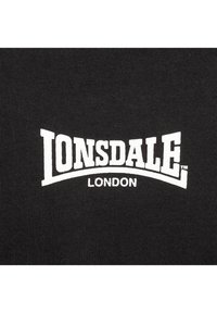 Sort T-shirt med "LONSDALE" og "LONDON" trykt i fed hvid tekst. Materialet har en glat tekstur og en tætsiddende pasform.