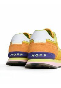 Rear view of multicolored sneakers featuring orange suede, white leather, yellow accents, and a purple and green sole with "HOFF" branding.