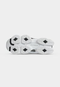 Подметка на маратонка New Balance в бяло и черно с диамантени шарки за сцепление и лого в центъра.