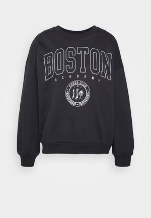Musta collegepaita, jossa etupuolella teksti "BOSTON ACADEMY" ja pyöreä shakkikerhon embleemi, jossa on shakkipaloja ja tähtiä.