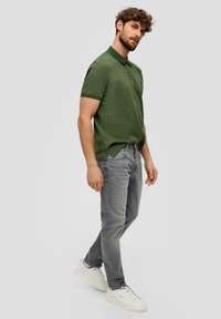 Groene poloshirt met kraag, korte mouwen; gecombineerd met lichtgrijze jeans; witte sneakers; casual fit met een gestructureerde afwerking.