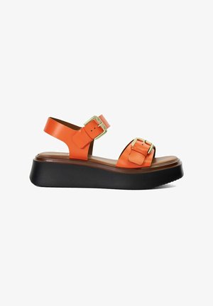 Orange leather platform sandal with two gold-tone buckles and black thick sole, side profile on white background.