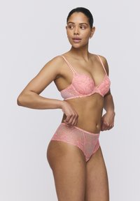 Roze kant beha en bijpassende slip met bloemige borduursels en golvende randjes. De stof heeft een doorschijnende textuur met verfijnde details.
