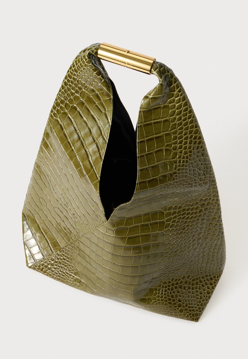 Sac à main vert en texture crocodile avec une poignée tubulaire dorée et un dessus ouvert, présentant un design asymétrique unique et une finition brillante.