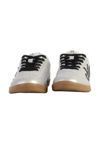 Scarpe da ginnastica bianche con lacci neri, suole in gomma e finitura liscia. Presentano un logo su un lato e dettagli di cucitura leggeri.