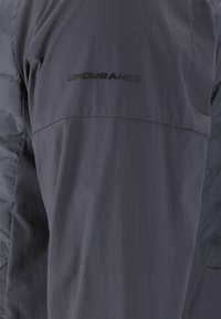 Veste gris foncé avec le mot « ENDURANCE » embossé en noir sur la partie supérieure de la poitrine.