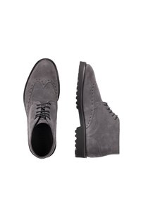 Zapatos de ante gris con detalles de brogue, puntera redondeada y suela de goma negra gruesa. Presentan múltiples ojales para los cordones y acentos texturizados.