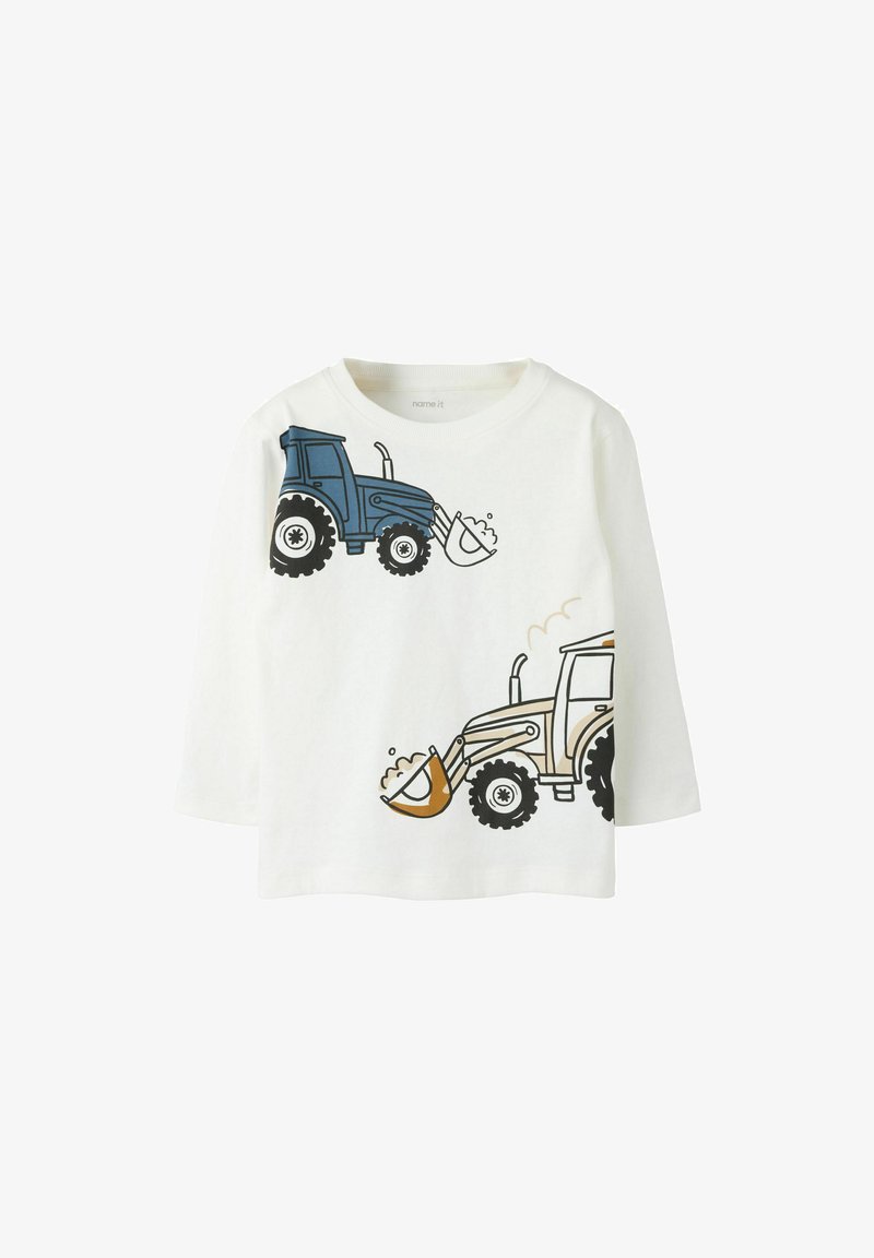 Chemise blanche à manches longues pour enfant avec des illustrations de tracteurs bleus et beiges ramassant de la terre à l'avant.
