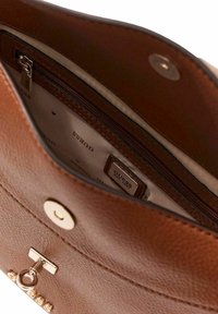 Intérieur d'un sac à main en cuir marron avec une poche zippée, une doublure crème et une fermeture à pression dorée. Comprend une étiquette de marque à l'intérieur.