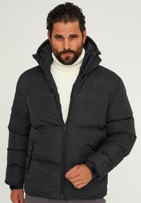 Schwarze Steppjacke mit durchgehendem Reißverschluss, hohem Kragen und verstellbarer Kapuze. Verfügt über gerippte Bündchen und Seitentaschen, gefertigt aus glattem, wasserabweisendem Material.