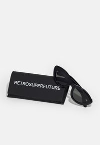 Occhiali da sole neri a forma di occhio di gatto, accompagnati da una custodia nera con testo bianco "RETROSUPERFUTURE". Finitura opaca liscia.