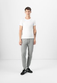 White short-sleeve t-shirt paired with gray sweatpants and black athletic shoes. The outfit features a relaxed fit and casual design.