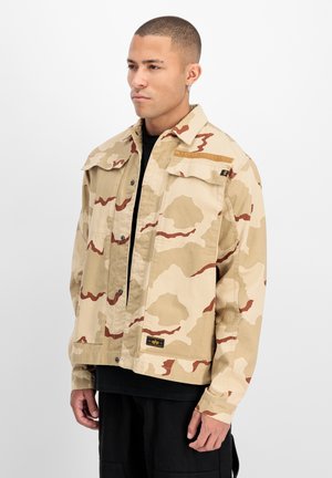 Beige camouflerende jas gemaakt van katoen, met grote opgestikte zakken, knoopsluiting en een logolabel aan de linkerkant bij de kraag.