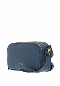 Blue leather crossbody bag with rounded rectangular shape, gold hardware accents, zip closure, and adjustable strap. Brand logo on front.