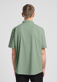Korte mouwen, gekraagde shirt in lichtgroen, met een gestructureerde stof en een ontspannen pasvorm, met een licht gebogen zoom ter hoogte van de taille.