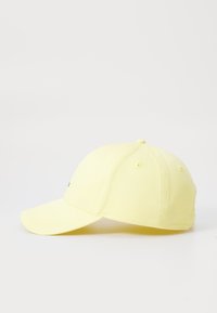 Casquette de baseball jaune en tissu, dotée d'une visière courbée et de perforations pour la ventilation, avec un logo brodé contrastant sur le panneau avant.