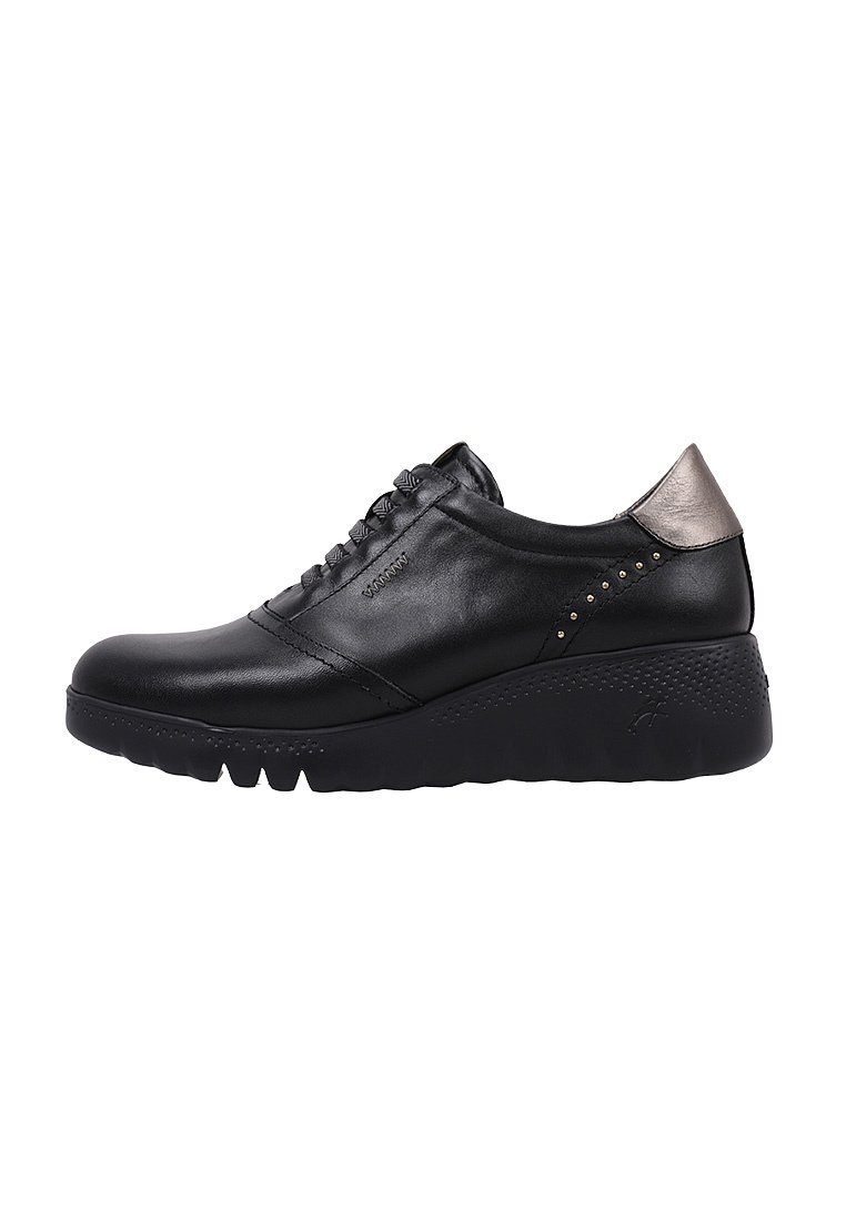 Sneaker en cuir noir avec un bout arrondi, un design à lacets, un accent métallique au talon et une semelle texturée avec de petites clous sur le côté.