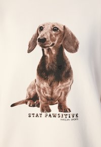 Hvid sweatshirt med et detaljeret grafik af en brun dachshund, med teksten "STAY PAWSITIVE" og "MARC CAIN SPORTS" i sort nedenunder.