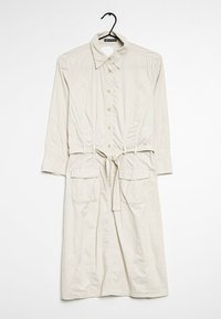 Helle beigefarbene Hemdkleid mit langen Ärmeln, durchgehender Knopfleiste, elastischem Bund, Bindegürtel und zwei vorderen Taschen. Glatte Stoffstruktur.