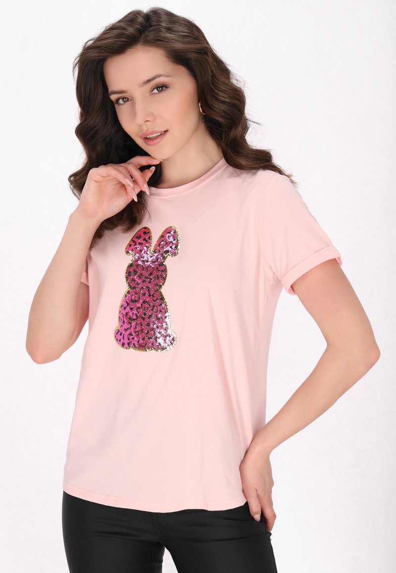 Světle růžové tričko s krátkým rukávem, které má design králíka se sekvínami v růžovém a černém leopardím vzoru. Měkká látka s kulatým výstřihem.